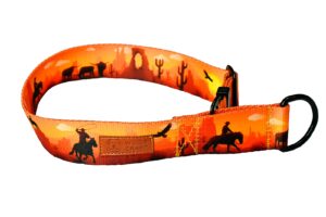 Zdjęcie przedstawia obrożę dla psa w typie półzaciskowym. Taśma ma kolor pomarańczowy i przedstawia kowbojów na koniach.